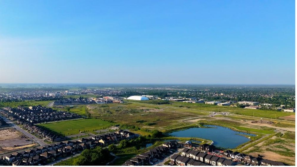 Aerial view of open land parcels beside a residential development