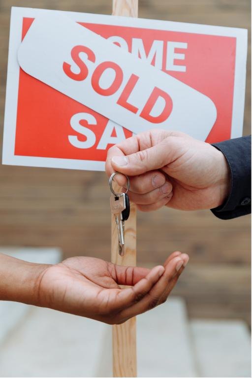 Keys changing hands in front of a sold sign